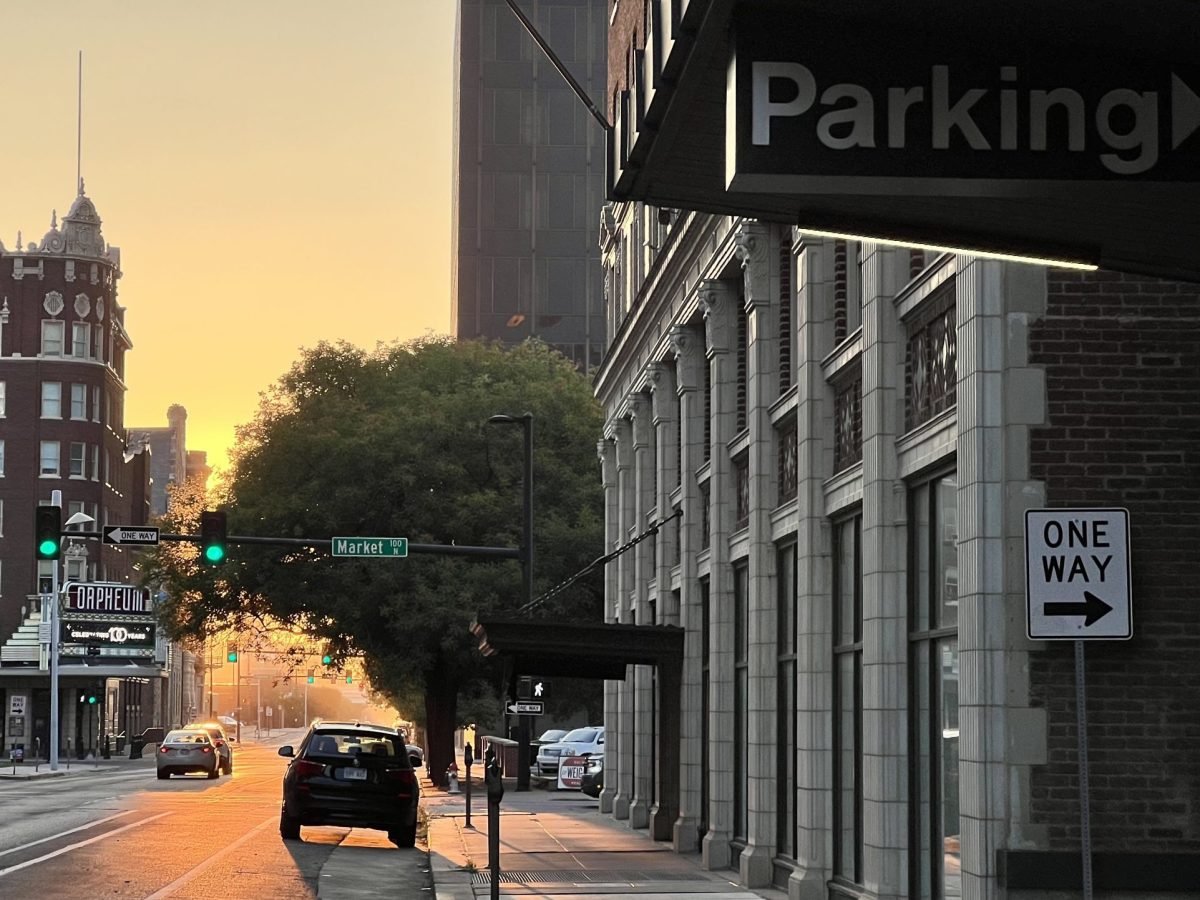 A car is parked on a street in downtown Wichita near parking meters and a sign for a parking garage.