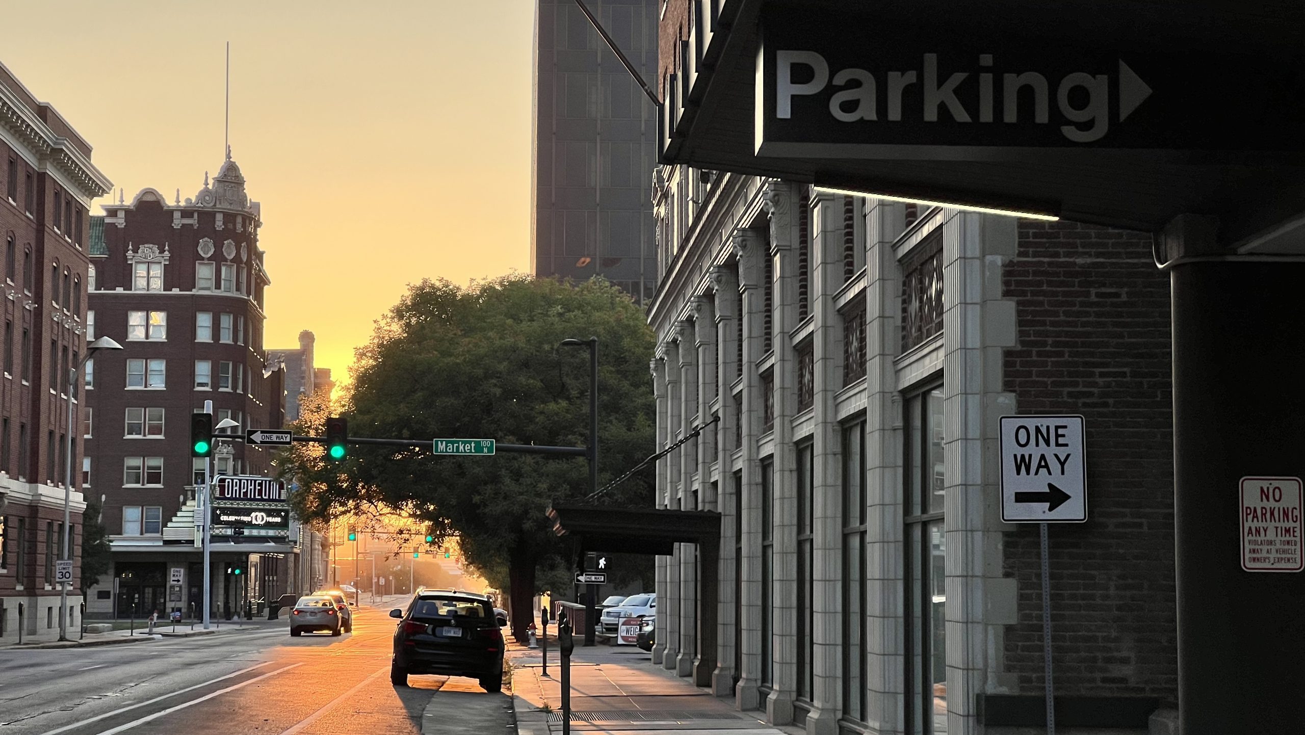 A car is parked on a street in downtown Wichita near parking meters and a sign for a parking garage.
