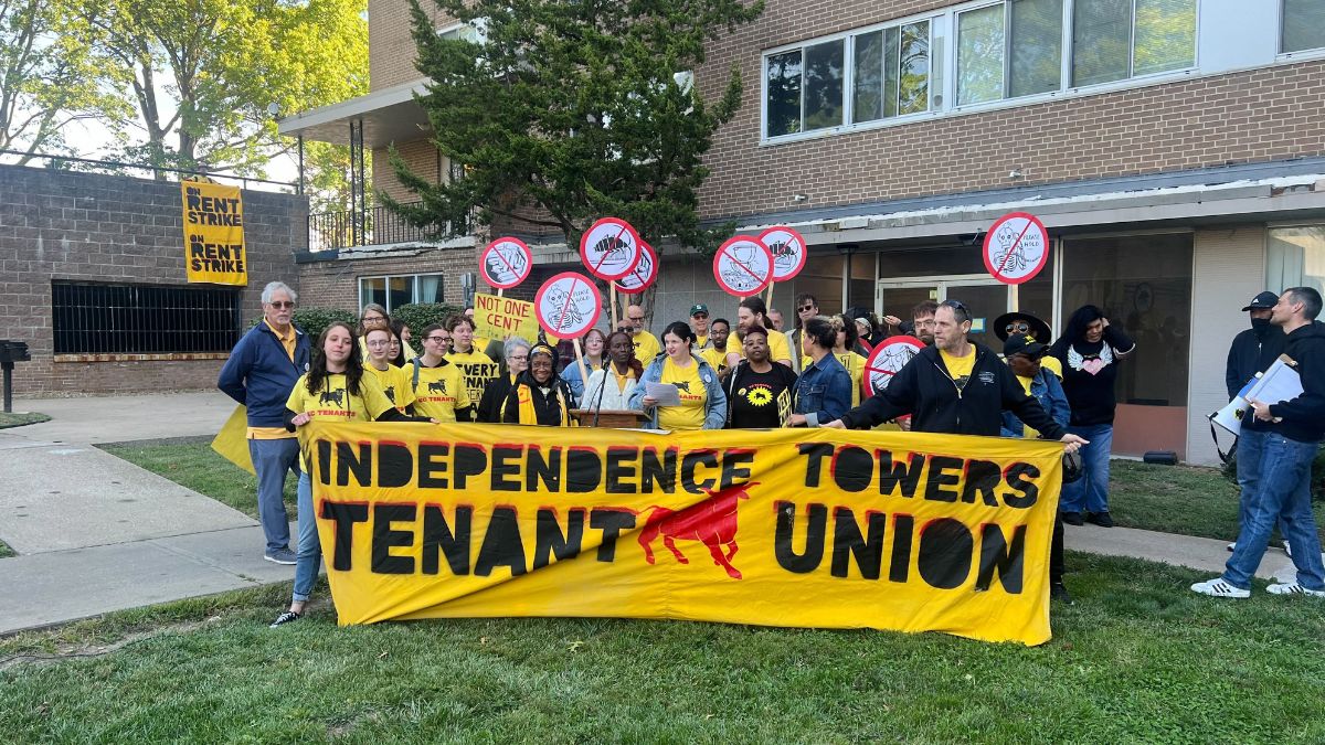 Protestors with the Independence Towers Tenant Union stand behind a podium.