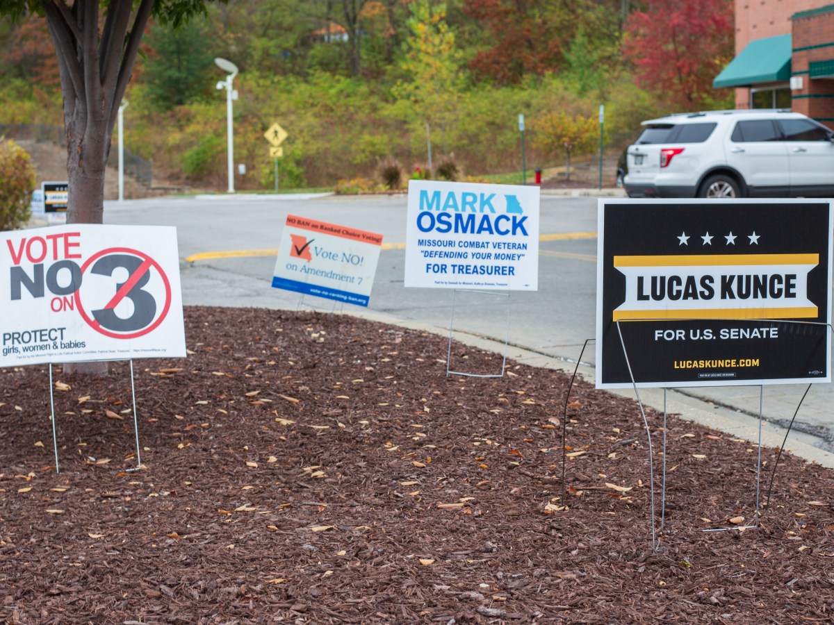 Yard signs in a mulch bed by a parking lot