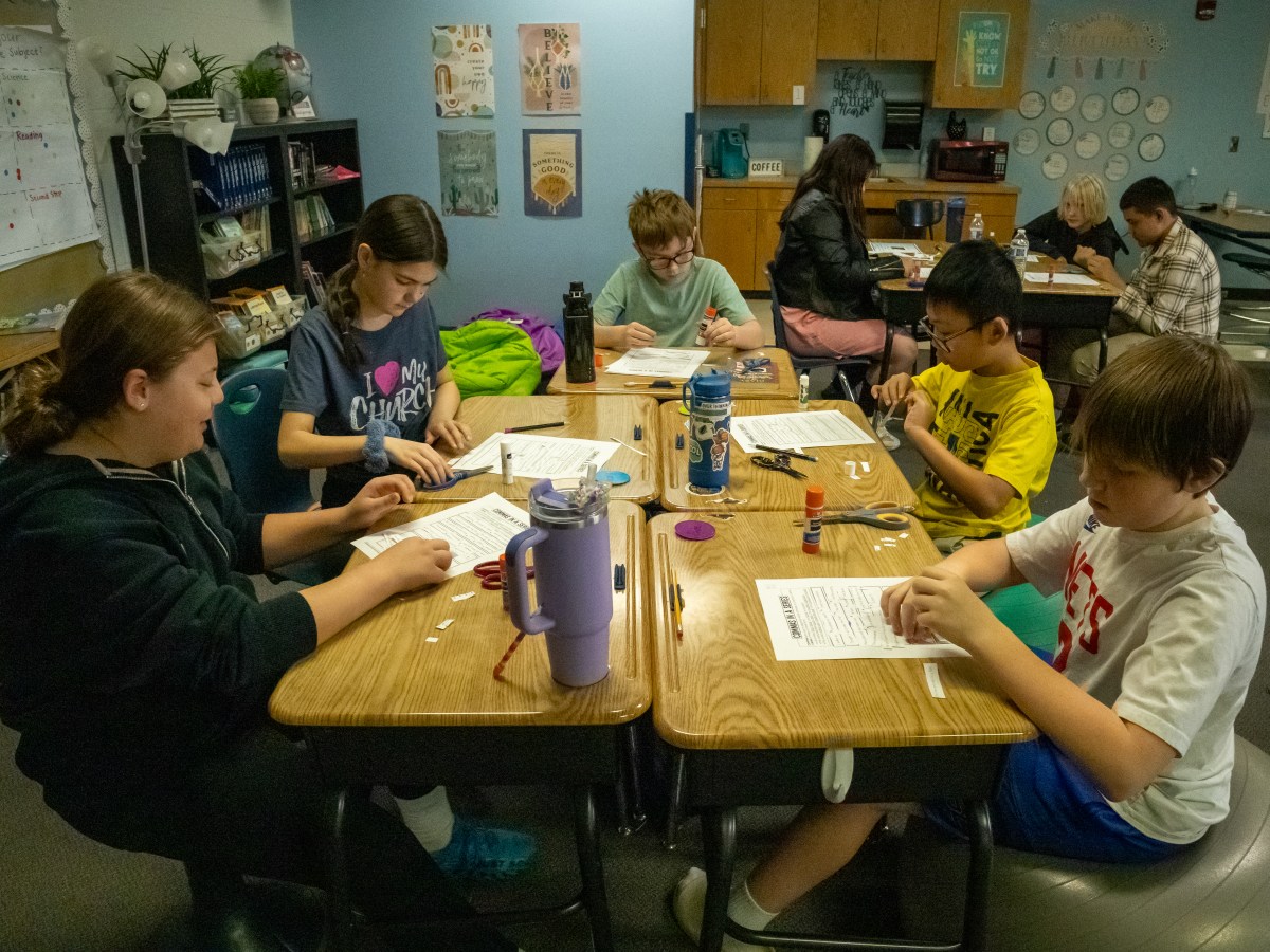Schoolchildren working at a table next to each other.