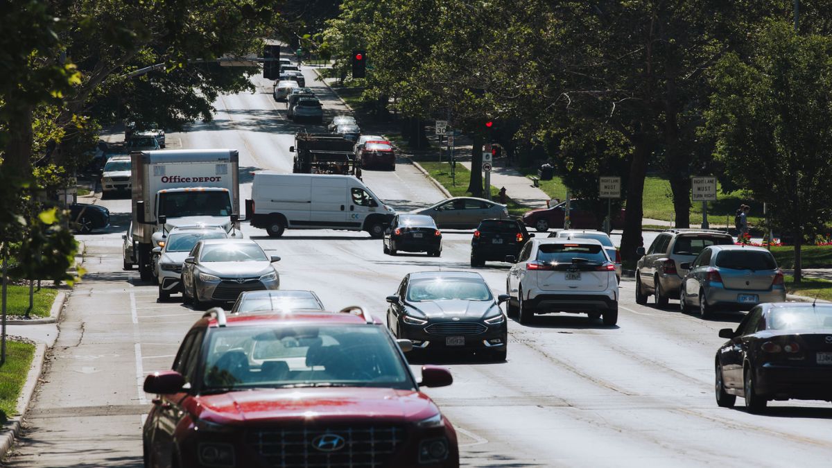 Cars driving on Armour Road. The streets are lining with parking spaces to make the driving area narrower and prevent car crashes.