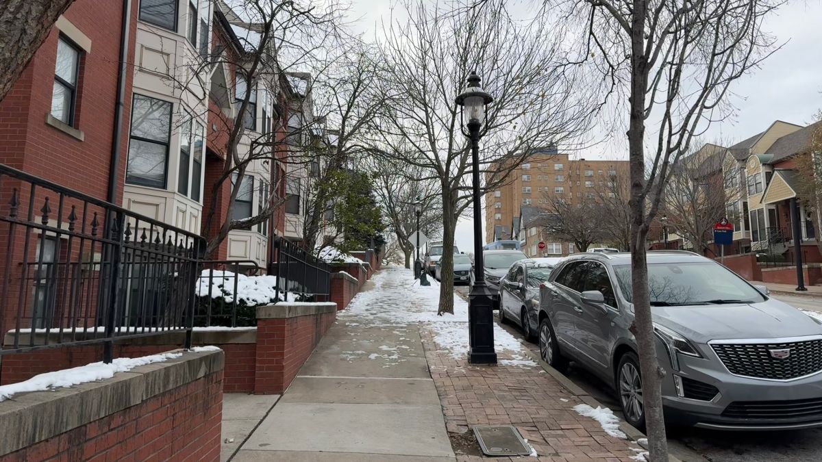 Snow and ice covering a sidewalk next to a row of townhouses.