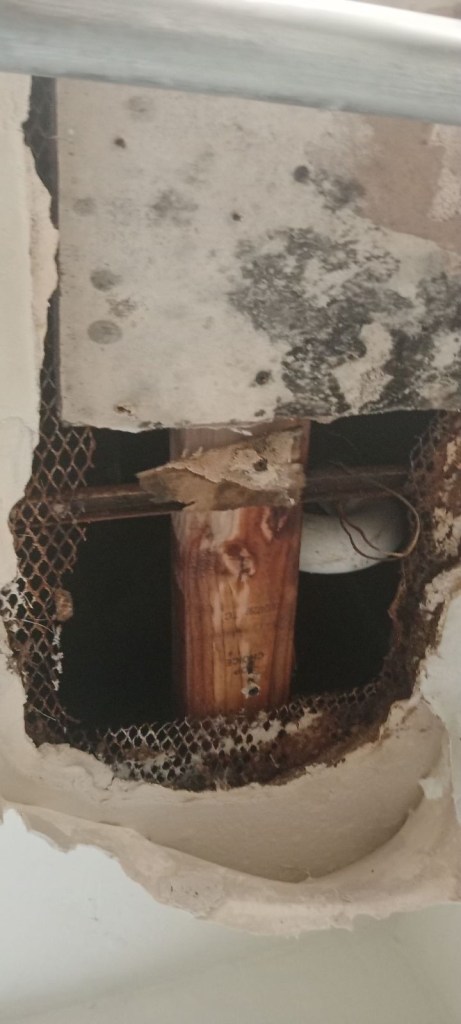 A big hole in the wall reveals pipes and other materials