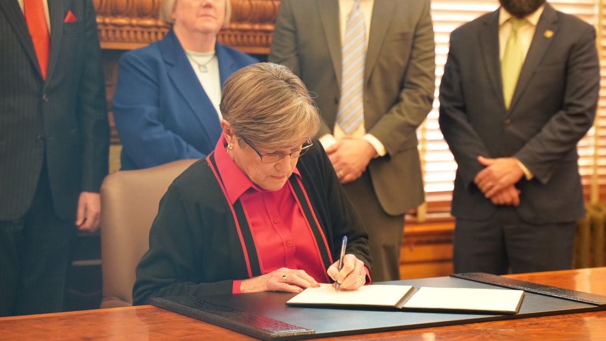 Governor Laura Kelly signing something at her desk.