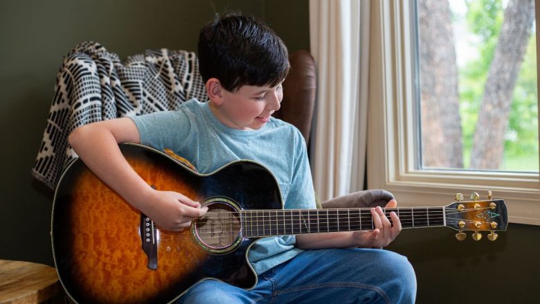 Horizon Academy student Henry Dunbar plays the guitar. His gecko, Oscar, is sitting on top of the guitar.
