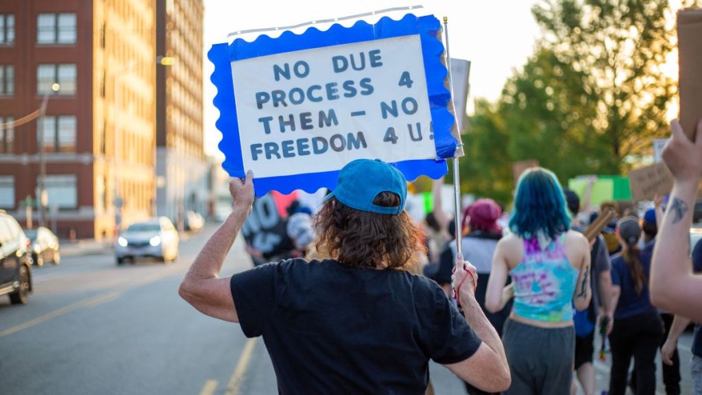 A protester at an immigrant rights demonstration holds a sign advocating for due process.