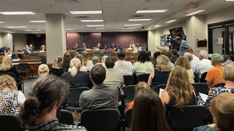 Residents and advocates sit in a committee hearing room, waiting to speak.