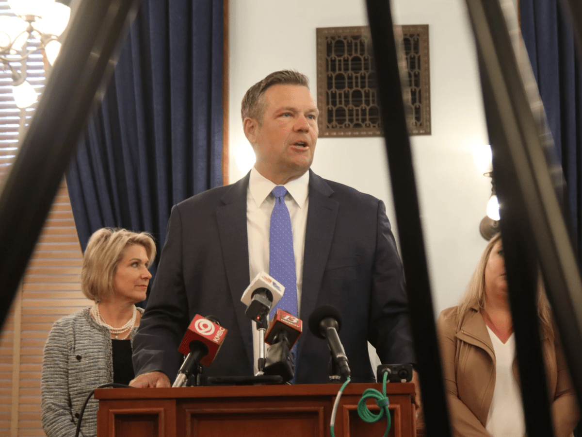 Kansas Attorney General Kris Kobach stands at a podium.