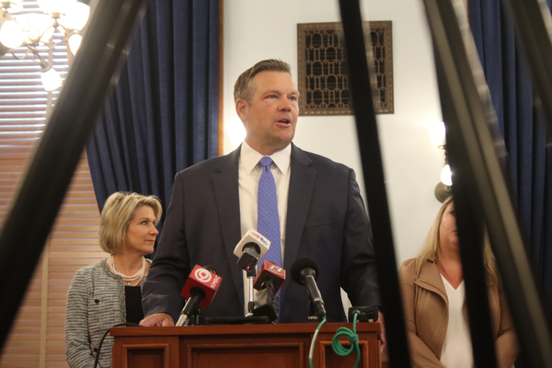 Kansas Attorney General Kris Kobach stands at a podium.