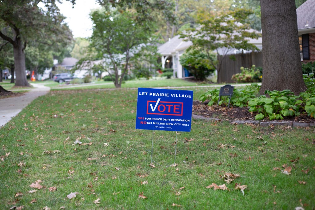 A blue lawn sign that says, "Let Prairie Village vote. Yes for police department renovation. No $23 million new city hall." and the URL to PV United's website at the bottom.