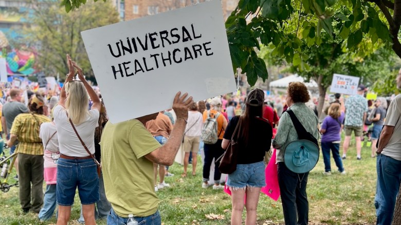 A protester carying a 'Universal Healthcare' sign at an Oct. 18 rally in Kansas City.