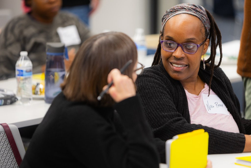 Two women having a conversation at a meeting.