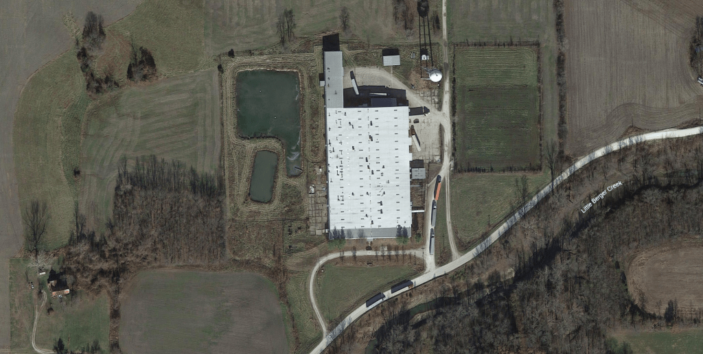A satellite image shows at least nine semitrailers in the process of unloading their cargo into a warehouse.