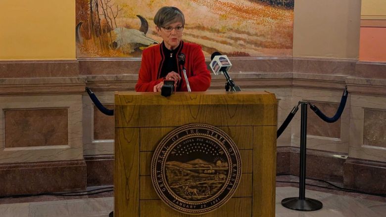 Laura Kelly stands at a podium talking to the press.