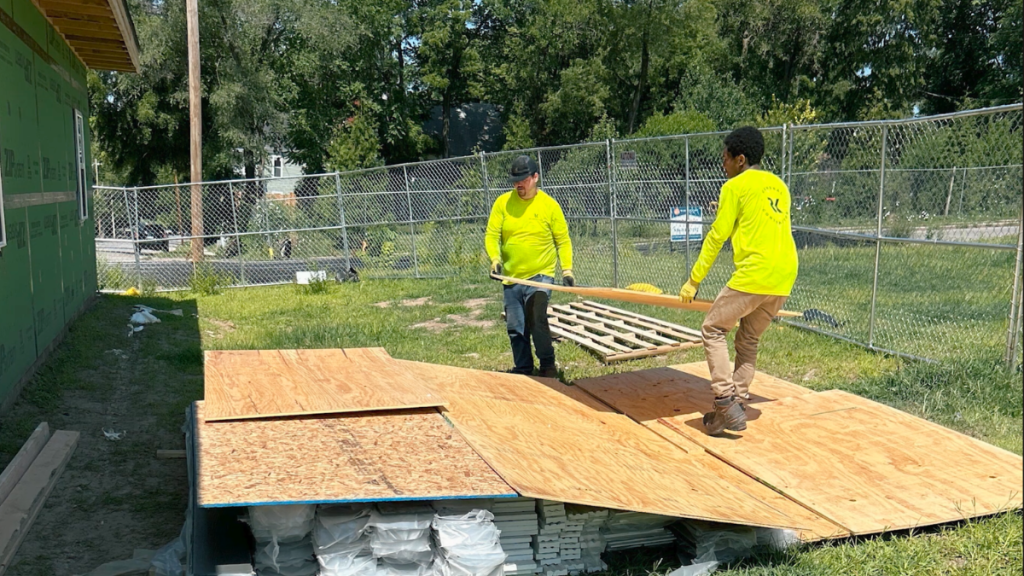 Two construction workers lay plywood flooring at a home building site in Kansas City’s Lykins neighborhood.