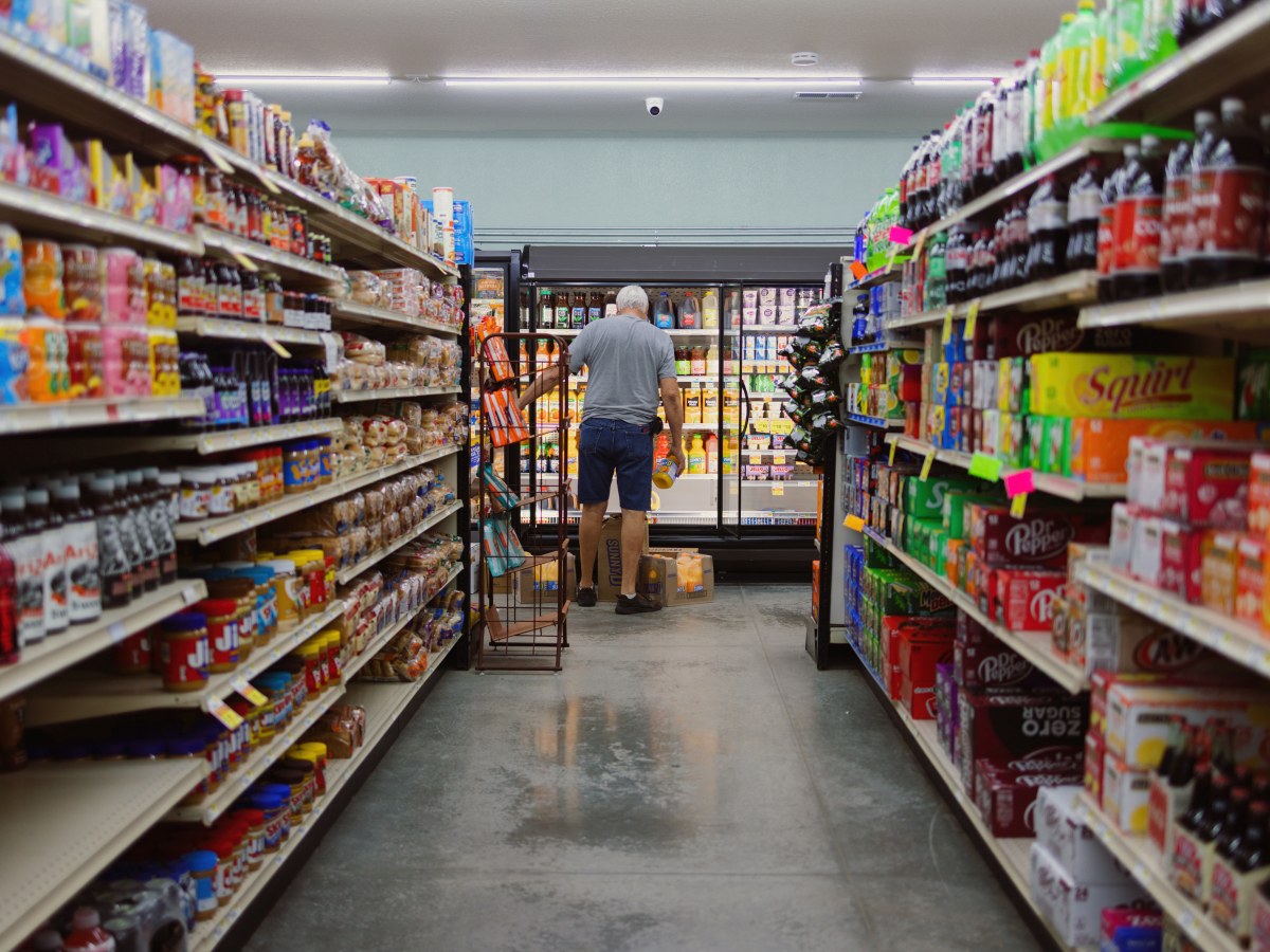 A man stocks a refrigerator at a grocery store.