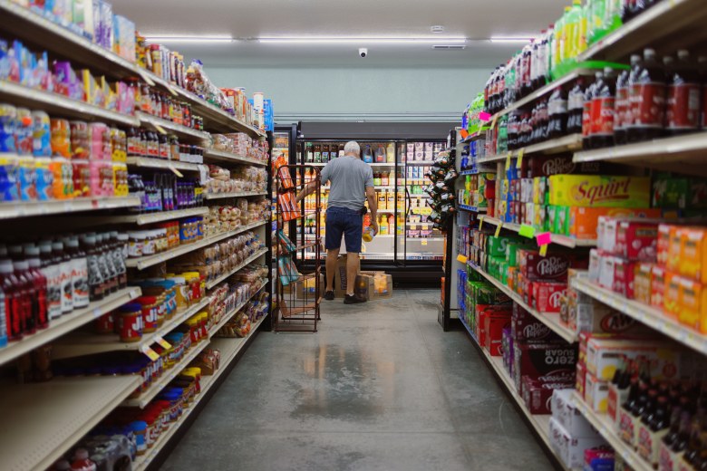 A man stocks a refrigerator at a grocery store.