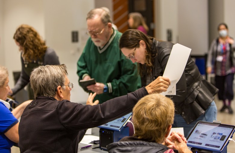 People stand in front of a desk at a polling place during the 2024 election.