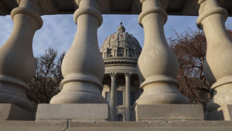 The Missouri Capitol building, seen through a line of columns.