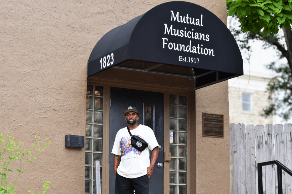 James McGee, secretary of the Mutual Musicians Foundation, stands in the doorway beneath the establishment's black arched awning at 1823 Highland Ave. in Kansas City's 18th and Vine Jazz District. A National Historic Landmark plaque is visible on the wall to his right.