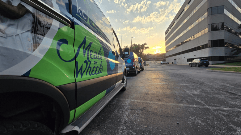 Meals on Wheels vans sit in a parking lot one evening.